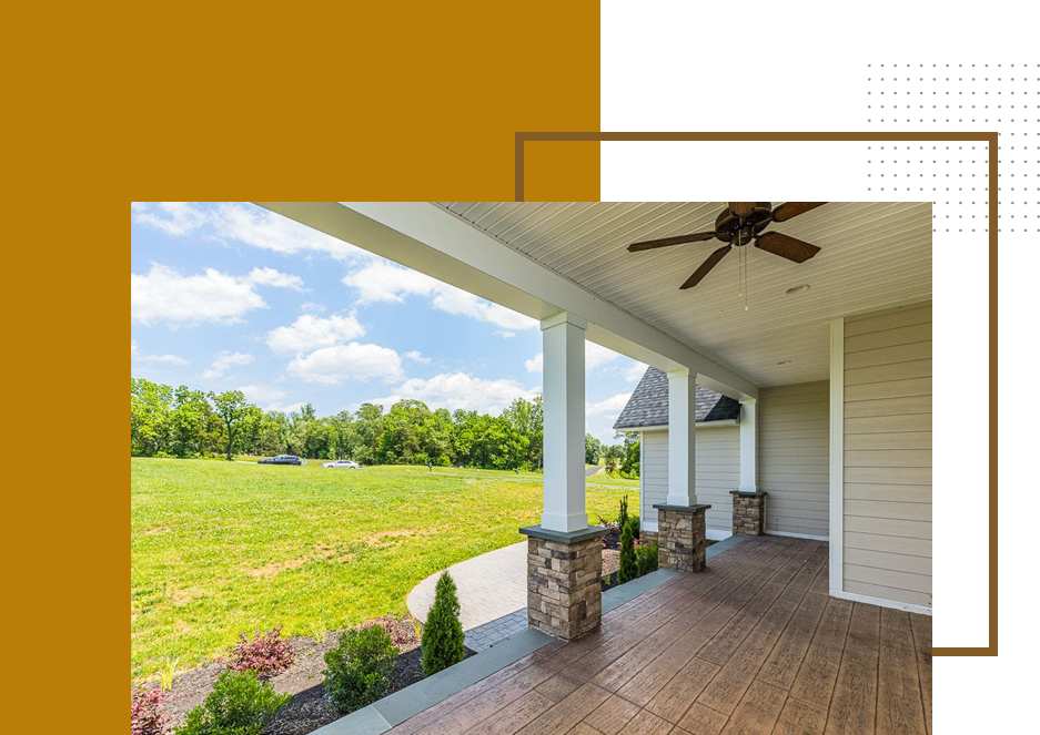 A porch with grass and trees in the background.